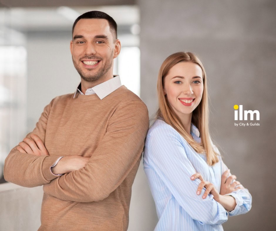 Confident professionals smiling with arms crossed in modern office setting.